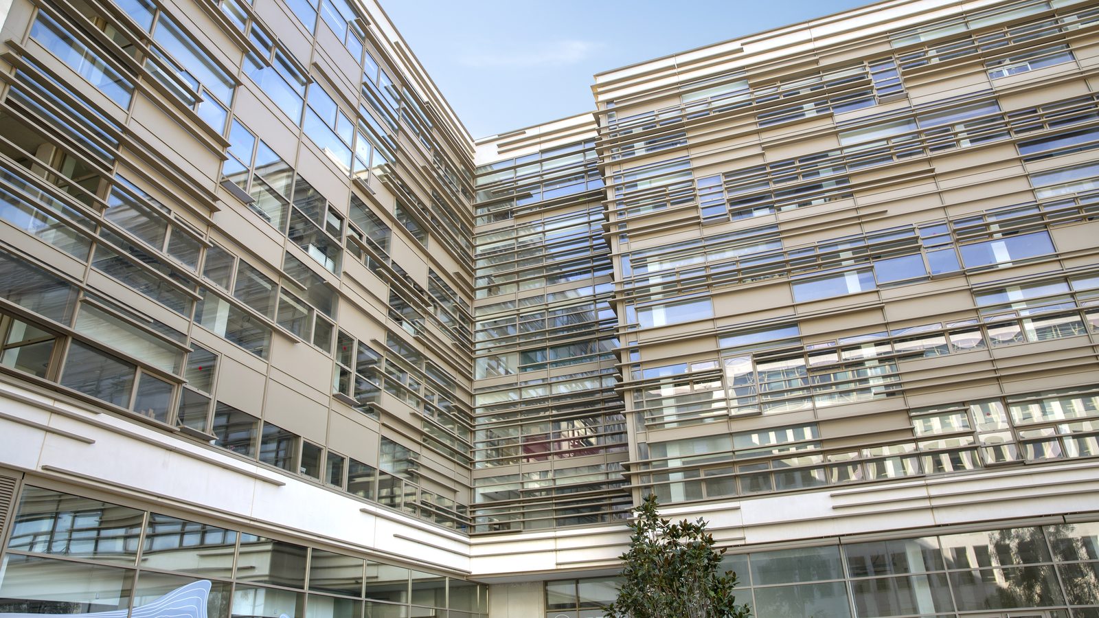 Façade vitrée du bâtiment ETIC en contre-plongée, lames de brise-soleil orientables sur plusieurs niveaux
