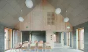 Salle polyvalente à charpente apparente dont le plafond en pente est habillé de dalles acoustiques en laine de bois.