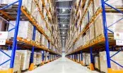 Allée d'entrepôt logistique bordée de rayonnages hauts, éclairée par une ligne de luminaires LED fixés en plafond.