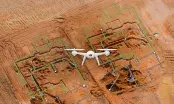 Vue aérienne d'un terrassement avec un drone en vol et le plan numérique du bâtiment superposé en vert sur les fouilles.