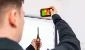 Technicien de dos filmant un coffre de volet roulant avec une caméra thermique compacte, sonde en main