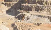Tombereaux et pelle en activité sur les gradins d'une carrière de granulats à ciel ouvert