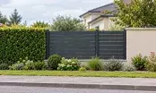Clôture à lames horizontales en aluminium gris installée en limite d'un jardin pavillonnaire