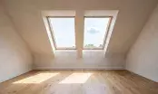 Combles aménagés éclairés par deux fenêtres de toit, rampants clairs et parquet chêne en pleine lumière
