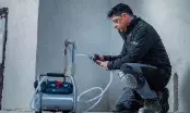 Technicien raccordant un flexible au compresseur Bosch GKO18V-51 pour un test de pression sur un réseau d'eau
