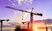 Chantiers de construction ralentis, grues immobiles sous un ciel nuageux, signe d'incertitude