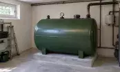Cuve à fioul domestique verte posée sur un socle béton dans un local technique, avec sa jauge et ses raccords.
