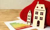 Maquettes de maisons en bois posées près d'une étiquette énergie de A à G et d'une écharpe rouge