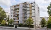 Immeuble d'habitation collective en rénovation, échafaudage bâché et panneaux d'isolant posés sur le pignon