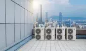 Quatre groupes extérieurs GREE alignés sur la terrasse technique d'un immeuble, devant une ligne d'horizon urbaine.