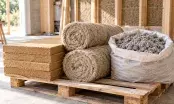 Panneaux de fibre de bois, rouleaux de chanvre et sac de ouate de cellulose posés sur une palette de chantier