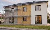 Façade de maison en cours d'isolation par l'extérieur, mur nu, panneaux isolants et enduit terminé