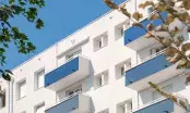 Façade d'un immeuble isolé par l'extérieur après finition, balcons bleus et enduit clair sous un ciel dégagé