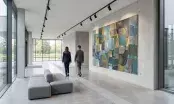 Grande toile contemporaine accrochée dans le hall lumineux d'un bâtiment tertiaire, banquette et circulation