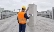 Opérateur en gilet orange scannant l'étiquette à QR code d'un élément en béton préfabriqué stocké