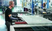 Un opérateur guide une grande plaque de verre sur la ligne de production d'un atelier industriel