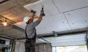Pose de panneaux isolants en sous-face de la dalle béton d'un garage, fixation mécanique au plafond