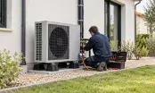 Installateur raccordant l'unité extérieure d'une pompe à chaleur le long d'une maison individuelle