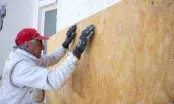Applicateur plaquant un panneau de laine de verre sur une façade, plots de colle blancs visibles