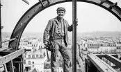 Ouvrier métallier d'époque sur une arche rivetée dominant les toits de Paris, visuel de l'exposition du SCMF