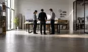 Réunion autour de plans dépliés et d'une maquette de bâtiment dans un bureau d'études contemporain