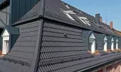 Toiture urbaine en tuiles terre cuite anthracite, avec chiens-assis en zinc, fenêtres de toit et arrêts de neige.