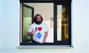 Hugo, personnage de la campagne VEKA, accoudé à une fenêtre PVC ouverte et désignant son t-shirt I love VEKA