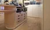 Comptoir de caisse sur mesure à plateau bois et façades laquées, avec tiroirs et niches techniques.