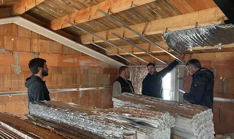 Un expert Actis accompagne des artisans sur un chantier pour installer des isolants réflecteurs.