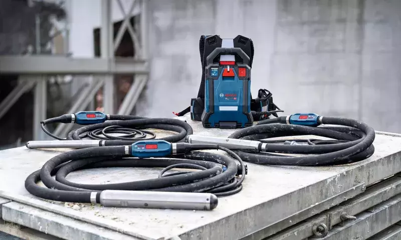 Unité d'alimentation dorsale Bosch et trois aiguilles vibrantes enroulées, posées sur une dalle de béton