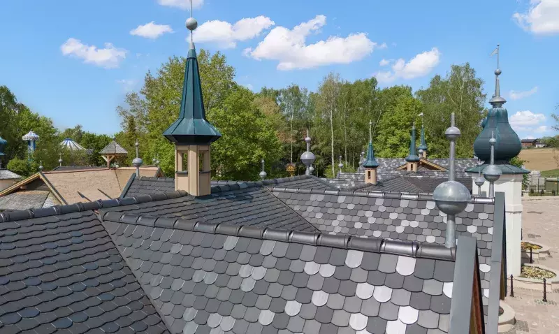 Les tuiles plates écaille, coupe segmentée, dans les couleurs noir mat et anthracite, et coupe ronde en titan silver, donnent à ce projet de référence une touche magique. 