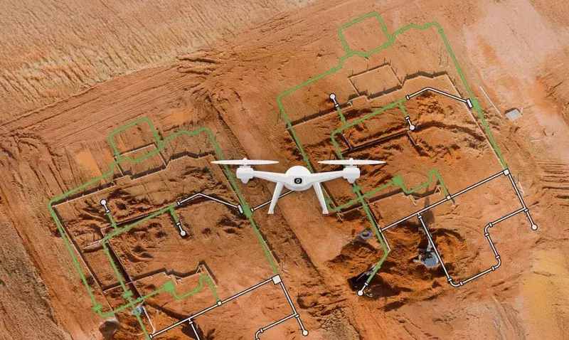 Vue aérienne d'un terrassement avec un drone en vol et le plan numérique du bâtiment superposé en vert sur les fouilles.