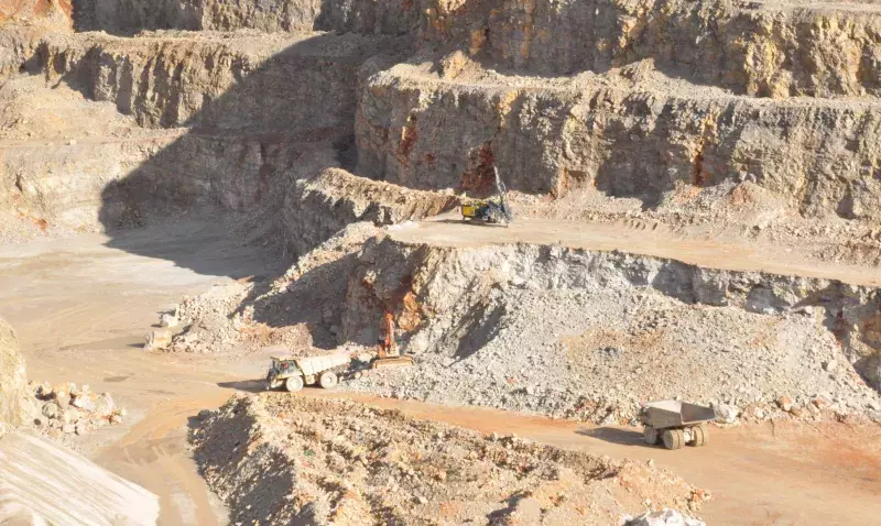 Tombereaux et pelle en activité sur les gradins d'une carrière de granulats à ciel ouvert