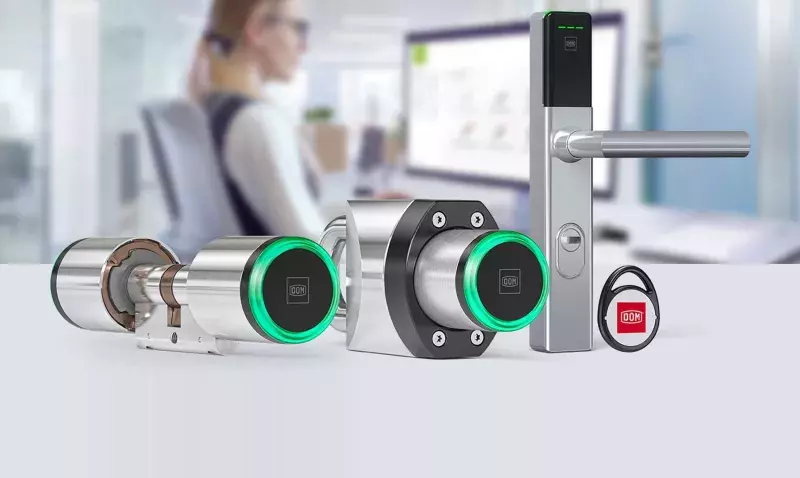 Cylindre électronique à anneau vert, béquille de porte connectée et badge porte-clés DOM-Metalux sur un plan clair