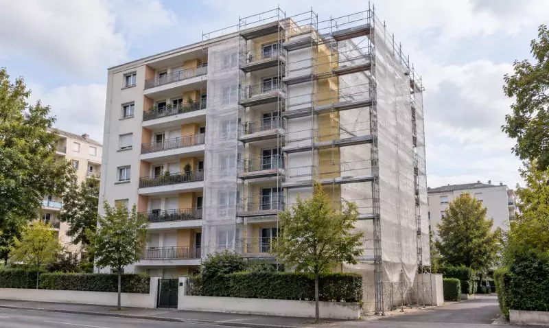 Immeuble d'habitation collective en rénovation, échafaudage bâché et panneaux d'isolant posés sur le pignon