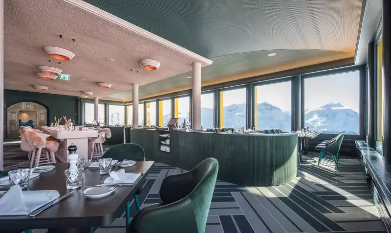 Restaurant panoramique de montagne au sol Flotex à chevrons verts, bar ondulé et baies vitrées sur les Alpes