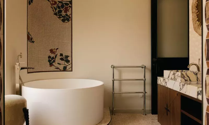 Baignoire ronde posée sur une estrade en mosaïque, panneau de mosaïque florale et meuble en marbre