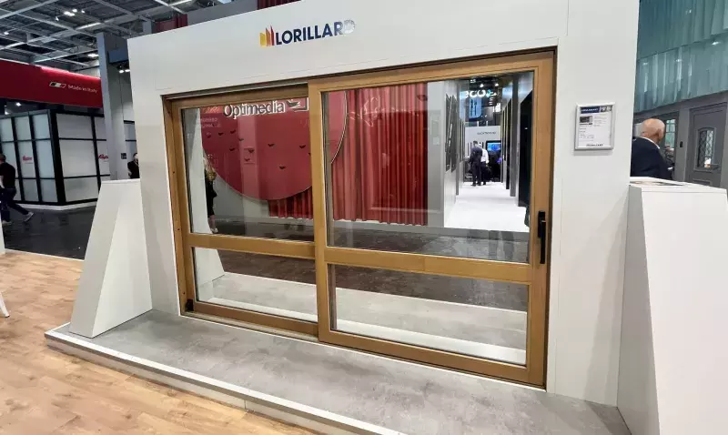 Coulissant bois à relevage Lorillard exposé sur un stand de salon, vantail en chêne clair et logo de la marque