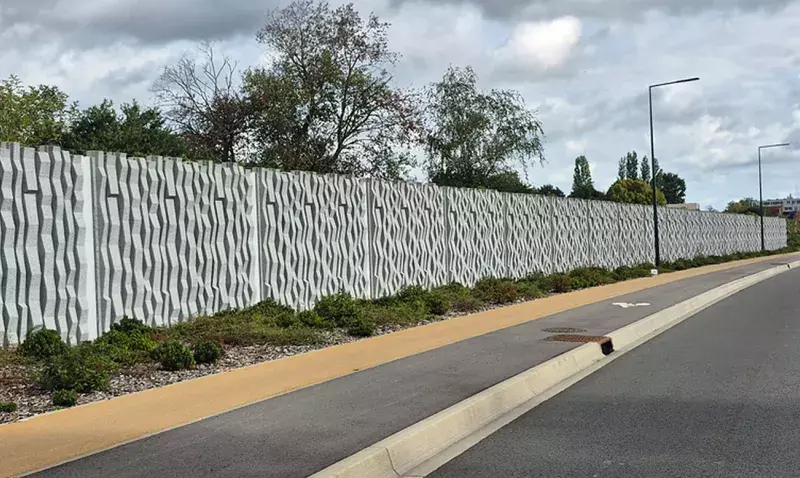 Mur anti bruit en béton préfabriqué à parement ondulé le long de la RD70, vu depuis la chaussée