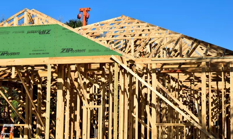 Chantier de construction d'une maison à ossature bois en Occitanie avec structure en bois apparente.