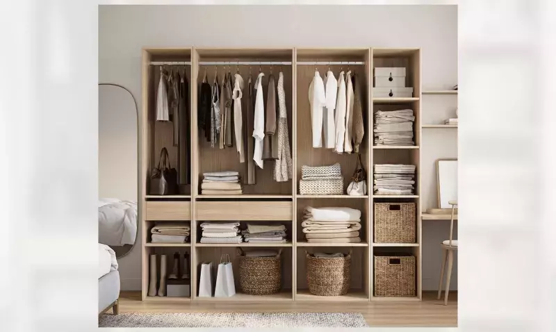 Composition de rangement modulable en chêne clair ouverte dans une chambre, tringles, étagères, tiroirs et paniers