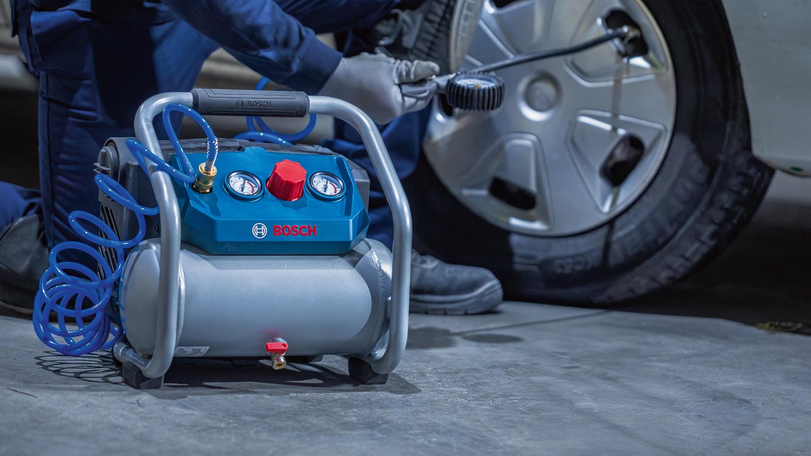 Professionnel gonflant le pneu d'un véhicule utilitaire avec le compresseur Bosch GKO18V-51 posé au sol