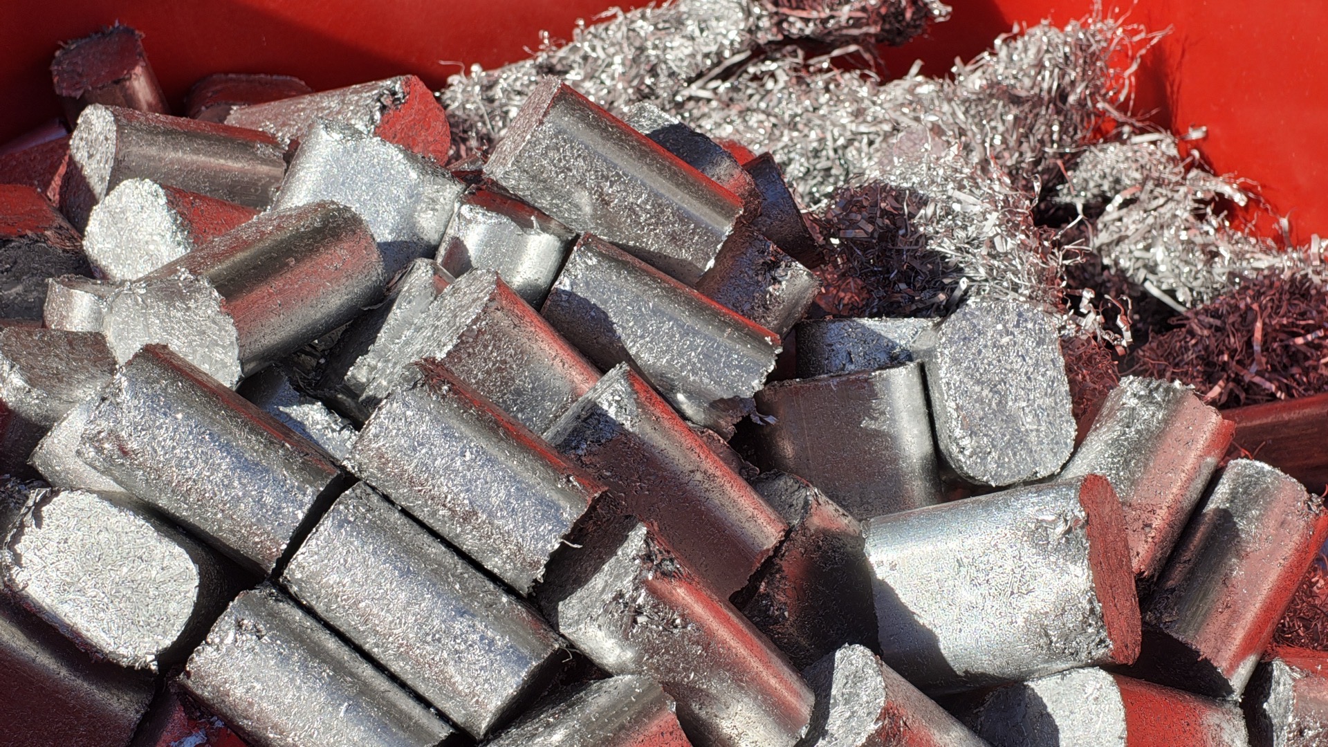 Briquettes de copeaux d’aluminium compactés dans un bac, à côté de copeaux encore en vrac